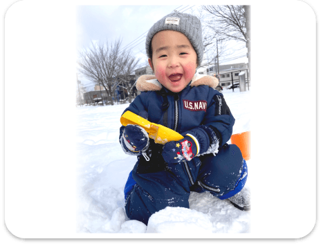 雪遊びをして楽しそうに笑う園児